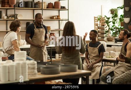 Manager talking with her team in a ceramics studio Stock Photo