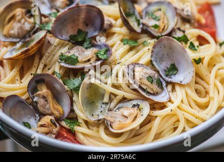 Spaghetti with clams, fresh cherry tomatoes, parsley leaves and ground black pepper, close up Stock Photo
