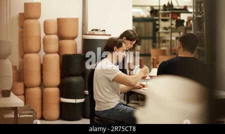 Ceramics designers talking together at a studio table Stock Photo