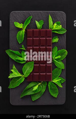 Dark organic cacao chocolate with mint leaves studio shot on isolated on black background Stock Photo