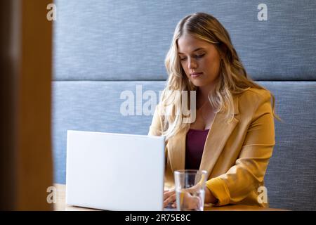 Plus size caucasian casual businesswoman with long blonde hair using laptop sitting at desk Stock Photo
