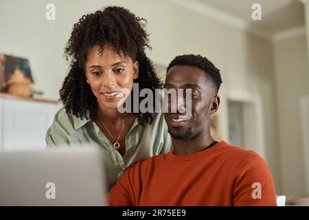 Smiling multiracial couple using a laptop together at home Stock Photo