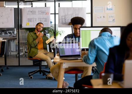 Thoughtful male creative and colleagues working at computers in office Stock Photo
