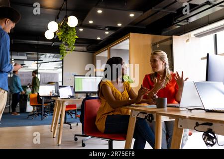 Diverse female colleagues in discussion using laptop in office Stock Photo