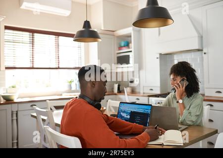 Young multiracial couple working remotely at a kitchen table Stock Photo