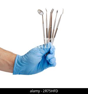 Man's hand in blue glove holding dental tools on white Stock Photo