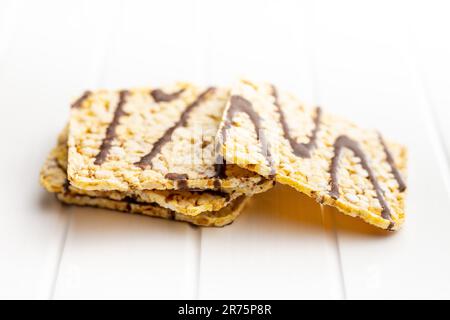 Puffed corn crackers chocolate covered on the white table. Stock Photo