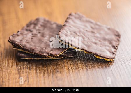Puffed corn crackers chocolate covered on the wooden table. Stock Photo