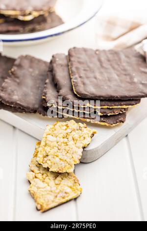 Puffed corn crackers chocolate covered on the white table. Stock Photo