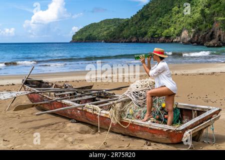 North America, Caribbean, Greater Antilles, Hispaniola Island, Dominican Republic, Sama Province, Sama Peninsula, Playa El Valle, Attractive woman standing in old fishing boat on beach Stock Photo