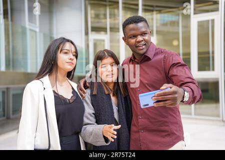 teamwork of women latin and a man black colleagues business people making a selfie with a mobile. Young multiracial workers with technology Stock Photo