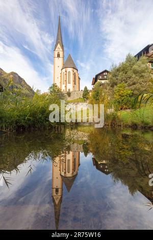 Parish church St.Vinzenz, Heiligenblut am Großglockner, during the day with reflection in small pond Stock Photo