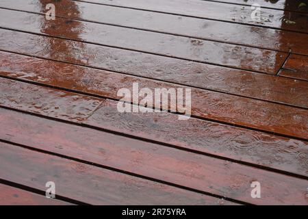 A heavy rain falls on a wooden deck, making interesting patterns. Stock Photo