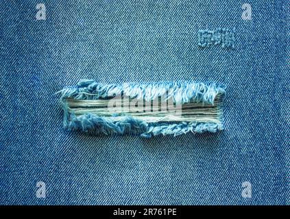 Torn Denim blue Jeans texture. Ripped denim blue cloth background. Recycling old jeans denim concept, banner with copy space. Stock Photo