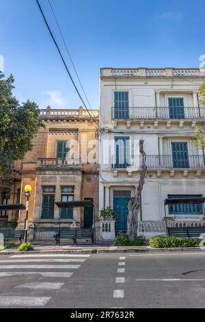 An aging building adorned with multiple balconies stands on a street corner in Mdina Old City Fortress Stock Photo