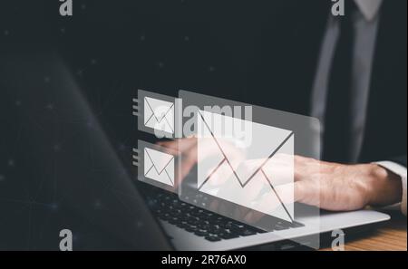 Businessman hands using Laptop typing on keyboard and surfing the internet on office table with email icon, email marketing concept, send e-mail or ne Stock Photo
