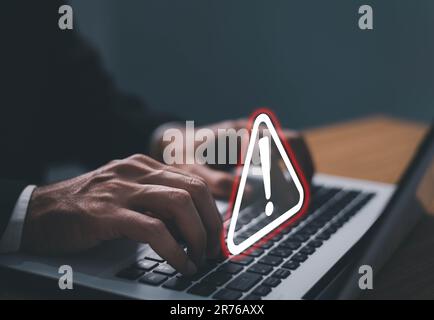 Error and maintenance alert. Businessman using computer laptop with triangle caution warning sing for notification error and maintenance concept. Stock Photo