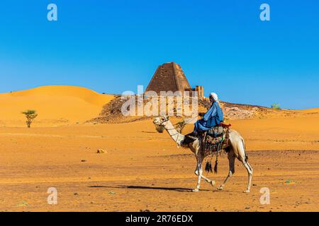 traditionally dressed arabs with their camels wait for tourists at the nubian pyramids at meroe in sudan Stock Photo