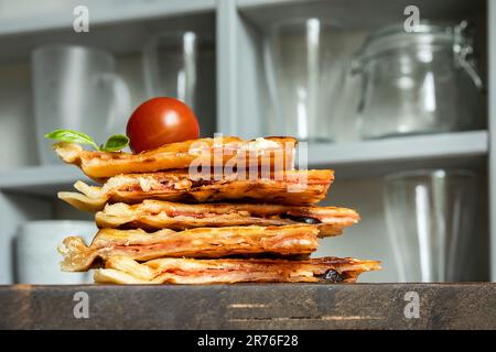 Homemade pizza waffle with tomato sauce, pepperoni, olives and parmesan cheese on a cutting board on the kitchen table Stock Photo