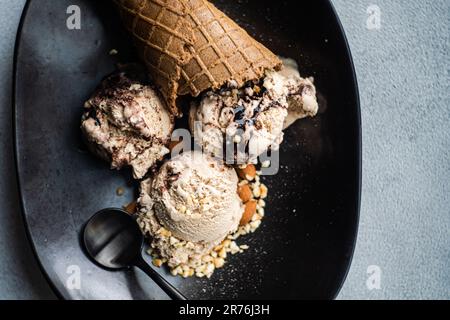 From above focus waffle cones with coffee and chocolate ice cream on the plate on concrete background Stock Photo