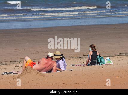 Portobello, Edinburgh, Scotland, UK. 13 June 2023. Heat is on at Porty beach and promenade for the mixed crowds out in the late afternoon after another misty start to the day. Temperature 21 degrees centigrade with a little cool breeze. Pictured: One male may have a little sunburn on his back. Credit: Arch White/alamy live news. Stock Photo