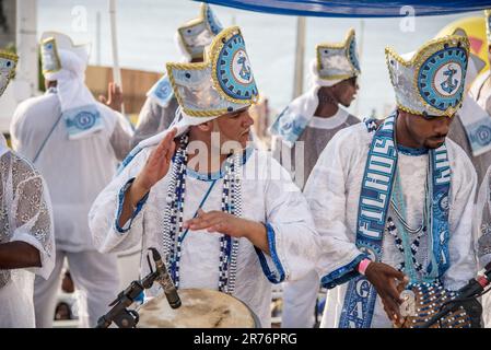 A group of five men in traditional cultural clothing playing various instruments including drums and guitars Stock Photo