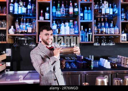 Young mixologist shaking a cocktail for his demanding clients. Concept: drinks, consumption, nightlife Stock Photo