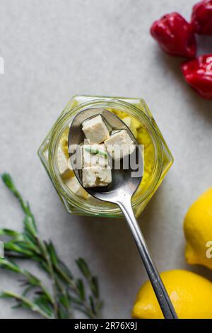 Top view of marinated feta cheese cubes in a spoon, Cheese cubes marinating in herb oil, flat lay of feta cheese in olive oil on a spoon Stock Photo