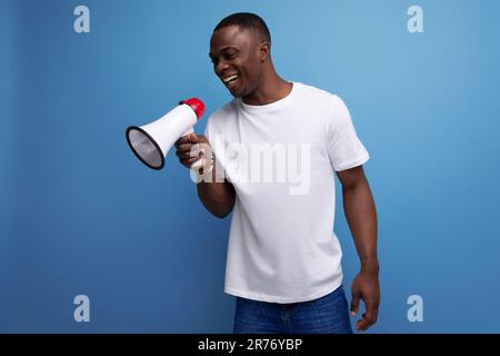 enthusiast 30 year old american male adult in white t-shirt speaks loudly using megaphone Stock Photo