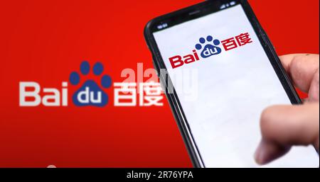 Beijing, CN, Feb 2023: A hand holding a phone with the Baidu website on the screen. Red background with blurred Baidu logo. Baidu is a Chinese multina Stock Photo