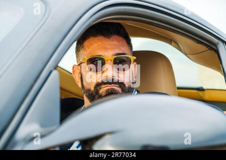 A handsome male in sunglasses driving his car Stock Photo