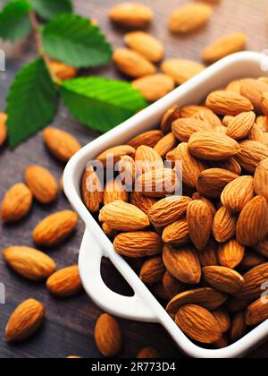 Peeled almonds. Almond kernels lie in a white plate. Top view with copy space. Advertising photo for commercial use in an online store or marketplace. Blank for design and infographics Stock Photo