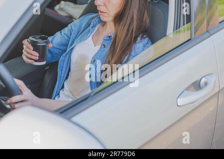 Coffee stain. Unrecognizable girl spilling coffee or tea on herself. Spoiled clothes. Concept of cleaning stains on clothes Stock Photo