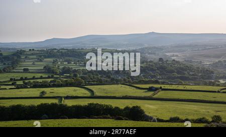 Morning light shines on the patchwork of farmland fields and woodland around North Brentor and Lydford villages under the hills of Dartmoor in West De Stock Photo