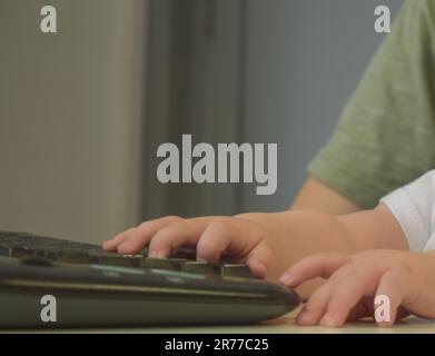 Hands of father and son on the computer keyboard Stock Photo