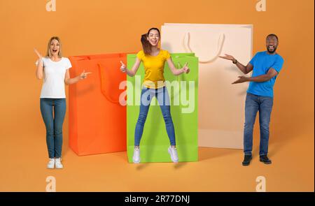 Multiracial shopaholics posing by huge shopping bags Stock Photo