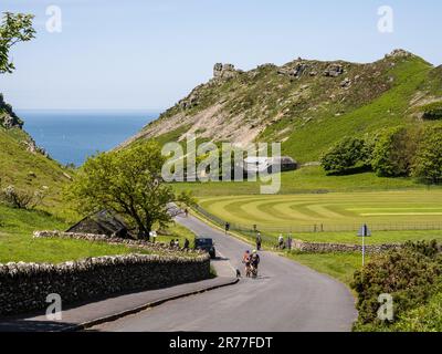 Walkers and cyclists enjoy a sunny day in the Valley of Rocks at Lynton on the Exmoor coast of North Devon. Stock Photo