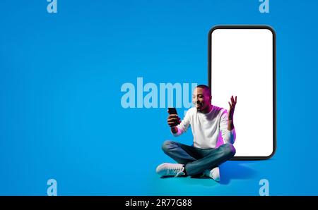 Excited young black man using smartphone and gesturing Stock Photo