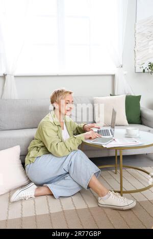 Mature female programmer working with tablet computer and laptop at home Stock Photo