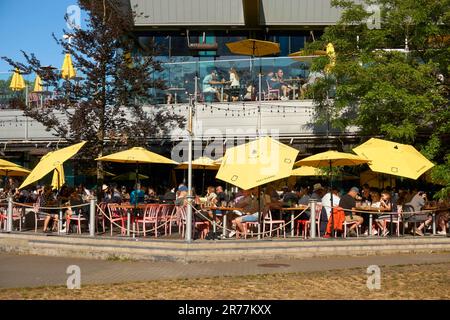 People sitting on the waterfront outdoor patio of Tap and Barrel restaurant in the Olympic Village on False Creek, Vancouver, BC, Canada Stock Photo