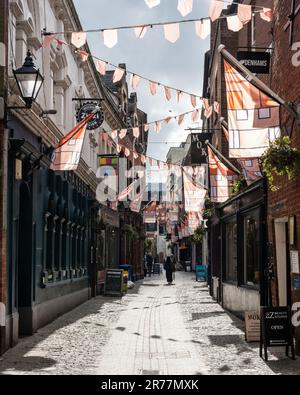 Pedestrians walk past shops on the narrow cobbled Gandy Street in Exeter city centre, Devon. Stock Photo