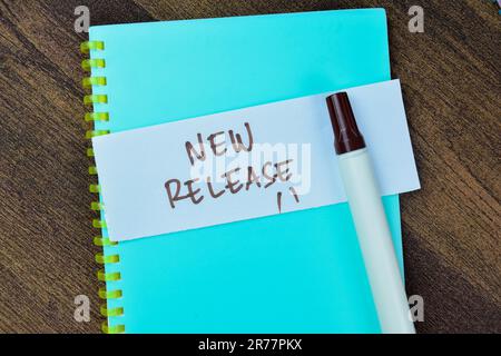 Concept of New Release write on sticky notes isolated on Wooden Table. Stock Photo