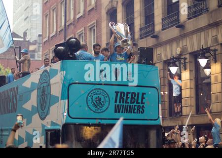 Manchester City football team open top bus parade during rain. Text Treble Winners June 2023 . Cup held up. Stock Photo