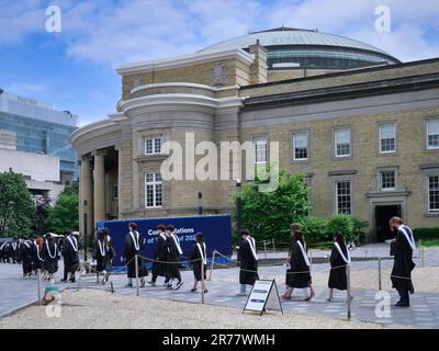 A procession of graduating university students in formal academic gowns go in to receive their diplomas Stock Photo
