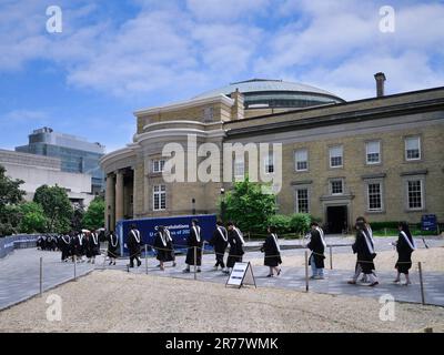 A procession of graduating university students in formal academic gowns go in to receive their diplomas Stock Photo