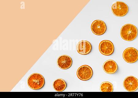 Dry slices of orange are laid out on a white and beige background top view. Orange chips on contrasting backgrounds. Useful snack. Proper nutrition. Stock Photo