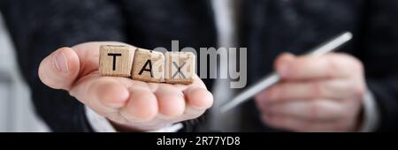 Man holding on palm tax word collected of wooden blocks letters Stock Photo