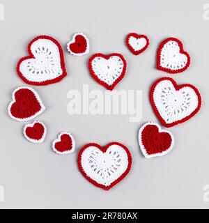 Happy Valentine's Day, Mother's Day and birthday greeting card. Red white crocheted hearts in the shape of a heart on a gray background. Stock Photo