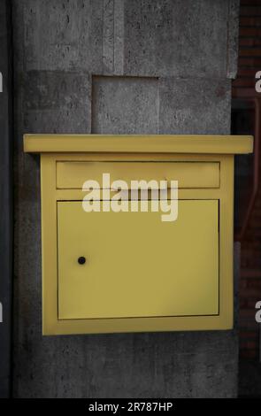 Yellow metal letter box on wall outdoors Stock Photo