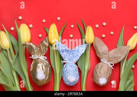 Flat lay composition with Easter bunnies made of paper and eggs on red background Stock Photo
